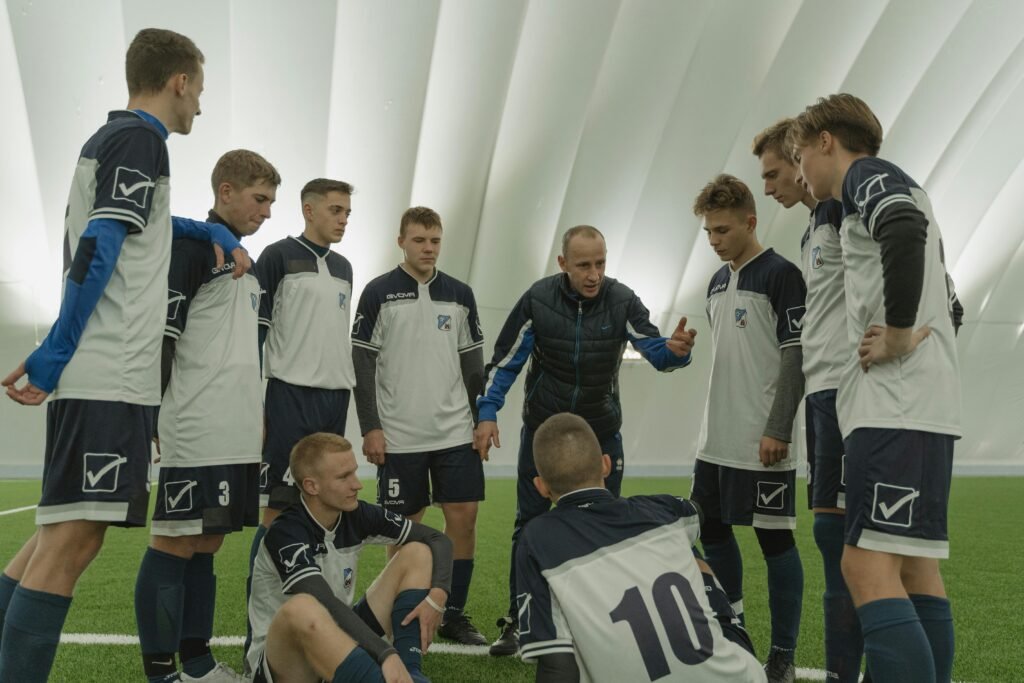 Football coach passionately instructing players on the pitch, symbolizing the leadership style behind the Arne Slot pose.