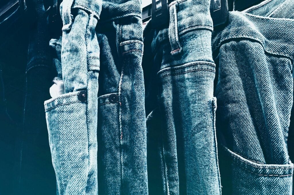 Close-up of several pairs of blue denim low rise jeans hanging on a rail, showcasing the classic 2000s-inspired style that’s trending in 2025, as popularized by Tara Reid